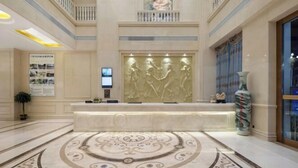 A lobby with a reception desk, a large decorative wall, and a patterned floor. - Vienna International Hotel (Du'an Station) (Du'an)