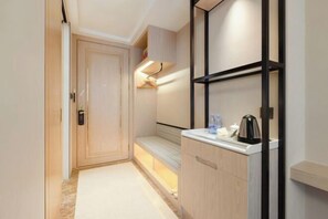 A narrow hallway with a door, a bench, a shelf with a kettle, and a small cabinet. - Vienna International Hotel (Du'an Station) (Du'an)