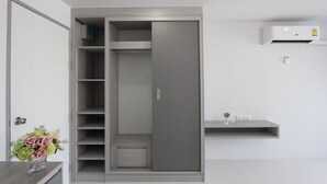 Un armadio moderno con ripiani multipli e porta scorrevole, un tavolino con un vaso di fiori e un condizionatore d'aria a parete.