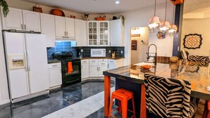 A modern kitchen with white cabinets, a black stove, a white microwave, and a glass island with stools. - Auburn Tiger Alumni Retreat on 20 acres (Salem)