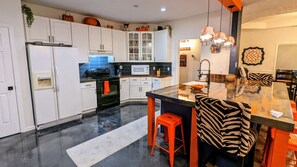 A modern kitchen with white cabinets, a black stove, and a glass island with stools.