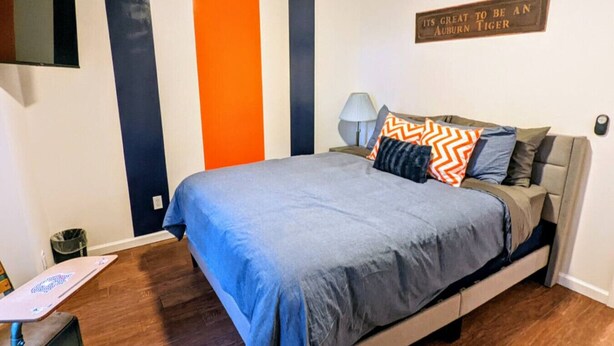 A bedroom with a bed, a desk, and a wall with a vertical stripe pattern. - Auburn Tiger Alumni Retreat on 20 acres (Salem)