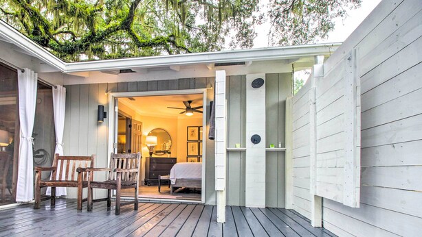 A wooden deck with a covered area leading to a bedroom with a bed, a chair, and a dresser. - 'The River Cottage' Isle of Wight Retreat w/ Dock (Midway)