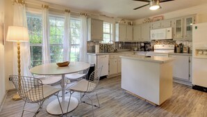 A modern kitchen with a central island, white cabinetry, and a dining area with wire chairs. - 'The River Cottage' Isle of Wight Retreat w/ Dock (Midway)