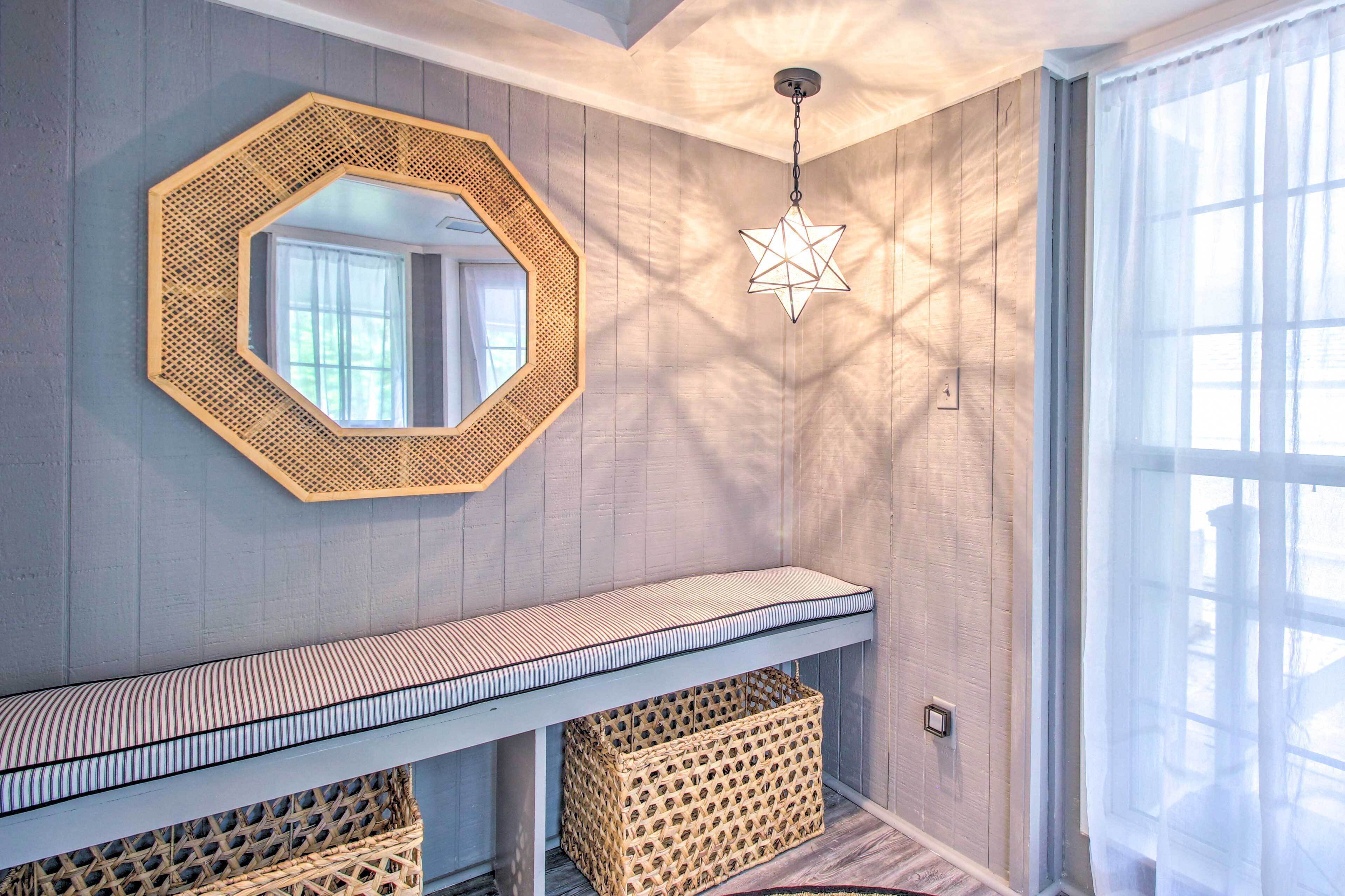 Une pièce avec un mur en bois, un cadre octogonal recouvert de miroirs, un luminaire suspendu en forme d’étoile, un banc à rayures et des paniers en osier.