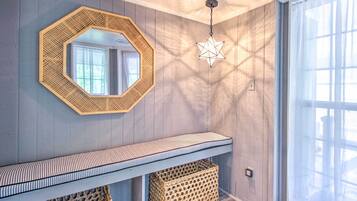 Une pièce avec un mur en bois, un cadre octogonal recouvert de miroirs, un luminaire suspendu en forme d’étoile, un banc à rayures et des paniers en osier.