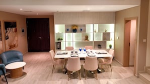 A modern dining area with a round table, six chairs, and a built-in shelving unit with decorative items. - Eagle Hills (Al-Fujairah)