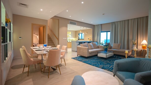 A modern living room with a dining area, a sofa set, and a kitchen in the background. - Eagle Hills (Al-Fujairah)