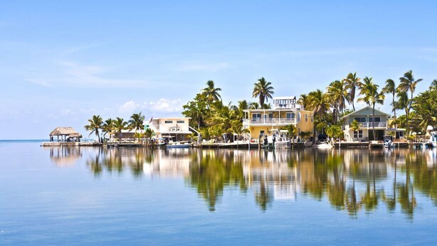 A waterfront property with a pool, a thatched-roof structure, and multiple buildings with balconies overlooking the water. - Lake It Easy: Relax in This Beautiful 3BR Canal Front Home on Summerland Key, Dockage & Dog-Friendly (Summerland Key)