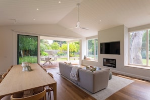 A spacious living area with a dining table, sofa, and TV.