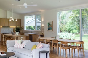 A modern kitchen with a dining area, large windows, and a view of the outdoors.
