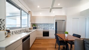 Eine moderne Küche mit Einbauofen, Kühlschrank und Essbereich mit Holztisch und Stühlen.