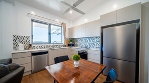 Eine moderne Küche mit eingebautem Geschirrspüler, einem Edelstahlkühlschrank und einem Essbereich mit Holztisch.