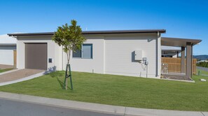 Ein modernes Einfamilienhaus mit Garage, einem kleinen Baum und einem umzäunten Garten.