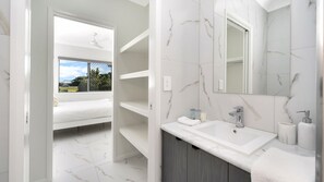 A modern bathroom with a large mirror, white marble tiles, and a built-in sink. - Stylish Stay Near The CBD (Oonoonba)