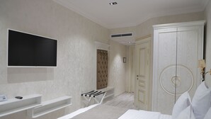 Een slaapkamer met een bed, een aan de muur bevestigde televisie, een kledingkast en een kaptafel met spiegel.