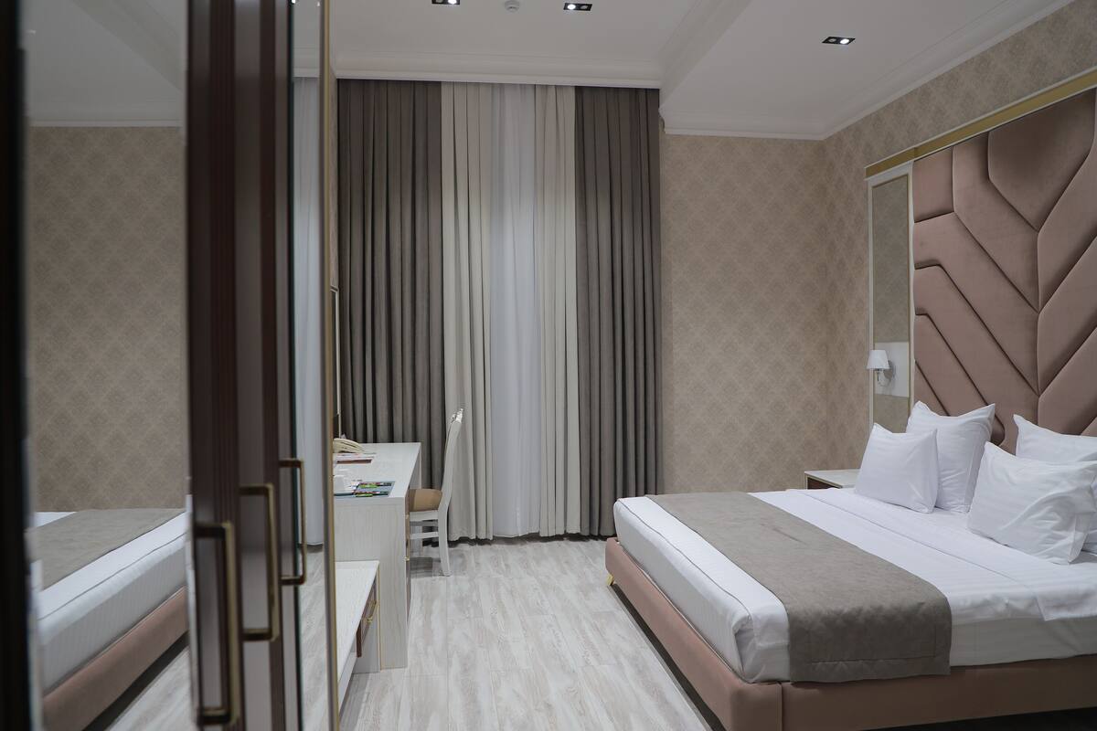A modern hotel room with a large bed, a desk, and a chair.