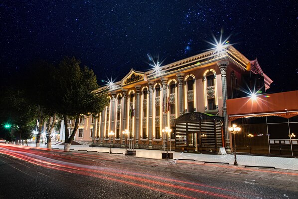 A historic building with ornate columns and a grand entrance, illuminated by street lights.