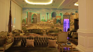 Een luxe lounge met zachte fauteuils, een muurschildering van een historische stadsgezicht en sfeervolle verlichting.