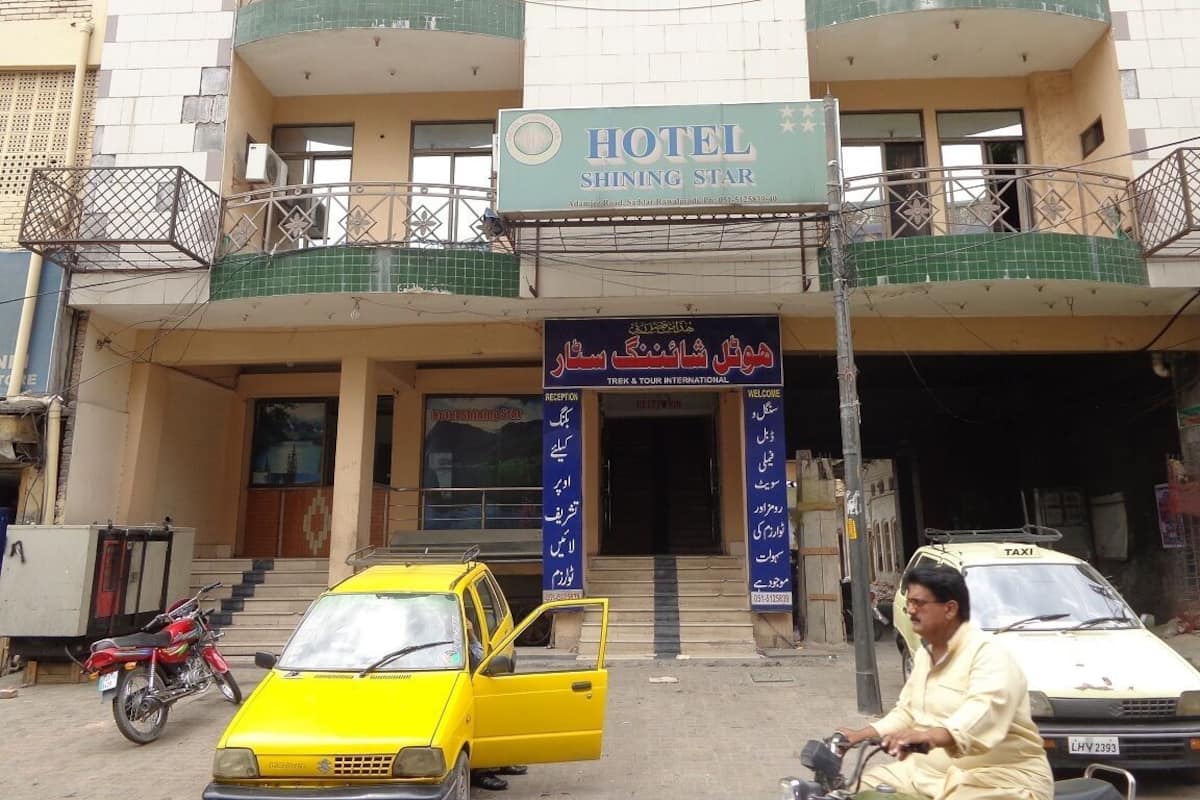 A hotel named "Shining Star" with a signboard, a reception area, and a taxi parked in front.