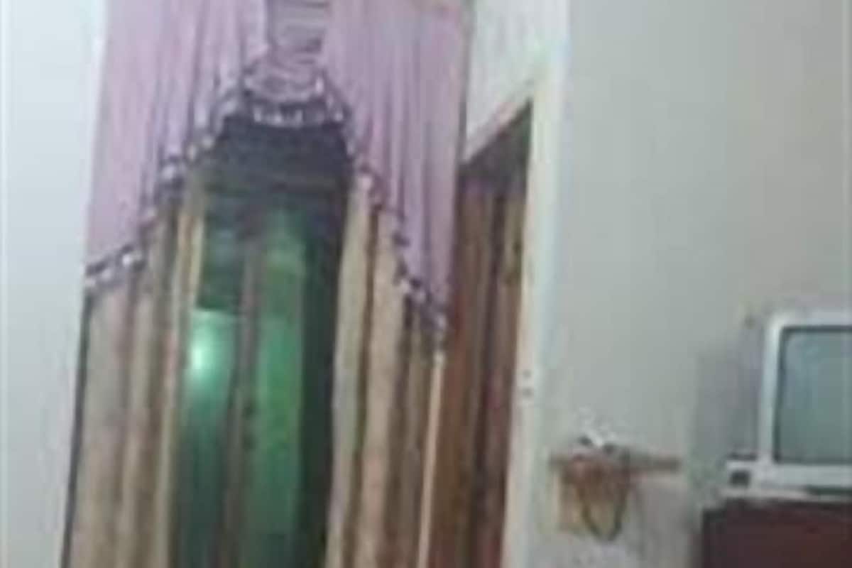 A room with a bed, a television on a stand, and a window with curtains.