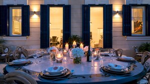 A round dining table set for six with candles, white flowers, and wine glasses. - Villa Callari 6 2 in San Felice Circeo (San Felice Circeo)