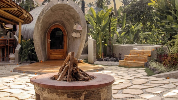 A stone archway leading to a wooden door, surrounded by tropical plants and a stone pathway. - Hot Stone Club Ubud (Sukawati)