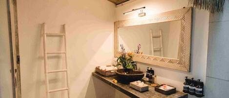 Un baño con un espejo grande, un lavabo, una escalera y una lámpara colgante.
