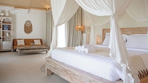 A bedroom with a canopy bed, a wooden bench, a sofa, and a wall-mounted shelf. - Hot Stone Club Ubud (Sukawati)