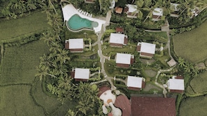 An aerial view of a resort with multiple buildings, a swimming pool, and lush greenery. - Hot Stone Club Ubud (Sukawati)