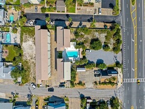 An aerial view of a residential area with multiple buildings, a swimming pool, and a road with a yellow line marking.