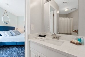 A hotel room with a bed, a bathroom with a sink, and a mirror.