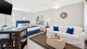 Ein modernes Schlafzimmer mit einem Bett, einem weißen Sofa, einem Couchtisch und einem Fernseher.