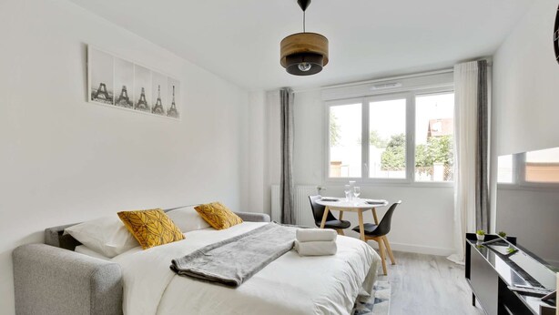 A hotel room with a bed, a desk, a chair, and a TV. - Chic studio near Paris - La Defense (Bezons)