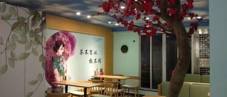 A restaurant with wooden tables and chairs, a mural on the wall, and a ceiling with a tree and flowers.