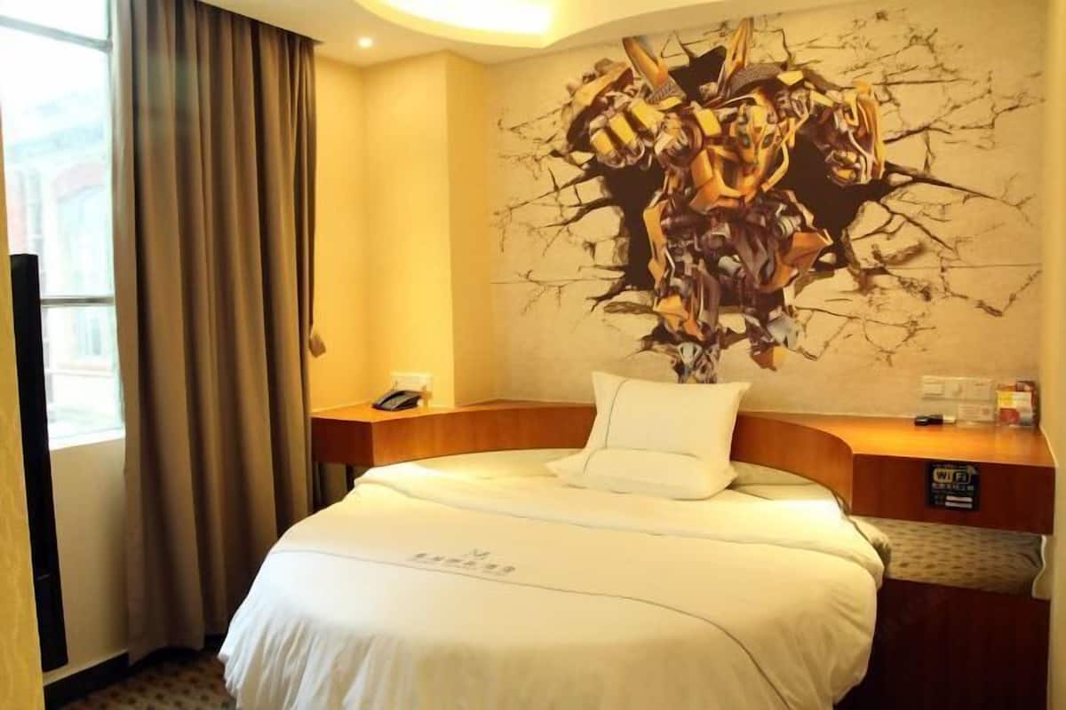 A hotel room with a bed, a desk, a phone, and a Wi-Fi sign.