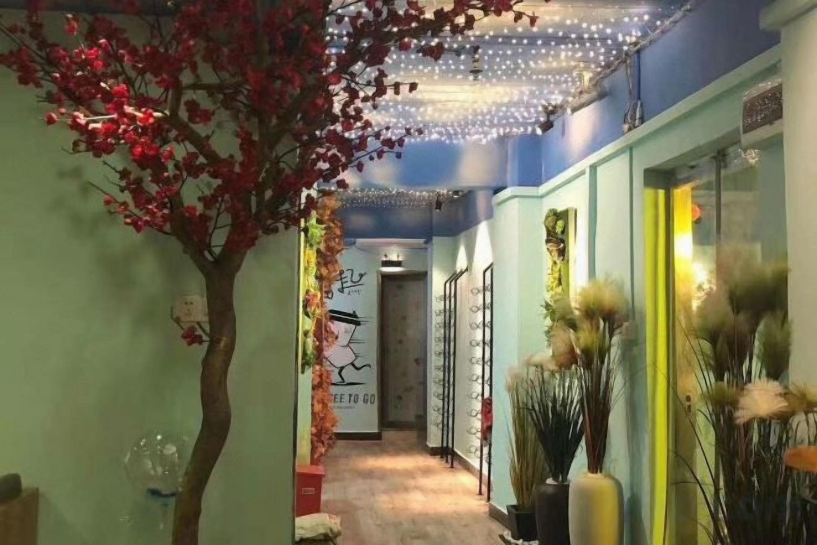 A hallway with a tree, decorative lights, and vases.