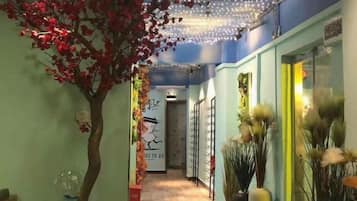Un pasillo con un árbol, luces decorativas y jarrones.