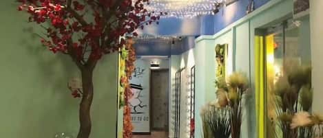 Un pasillo con un árbol, luces decorativas y jarrones.