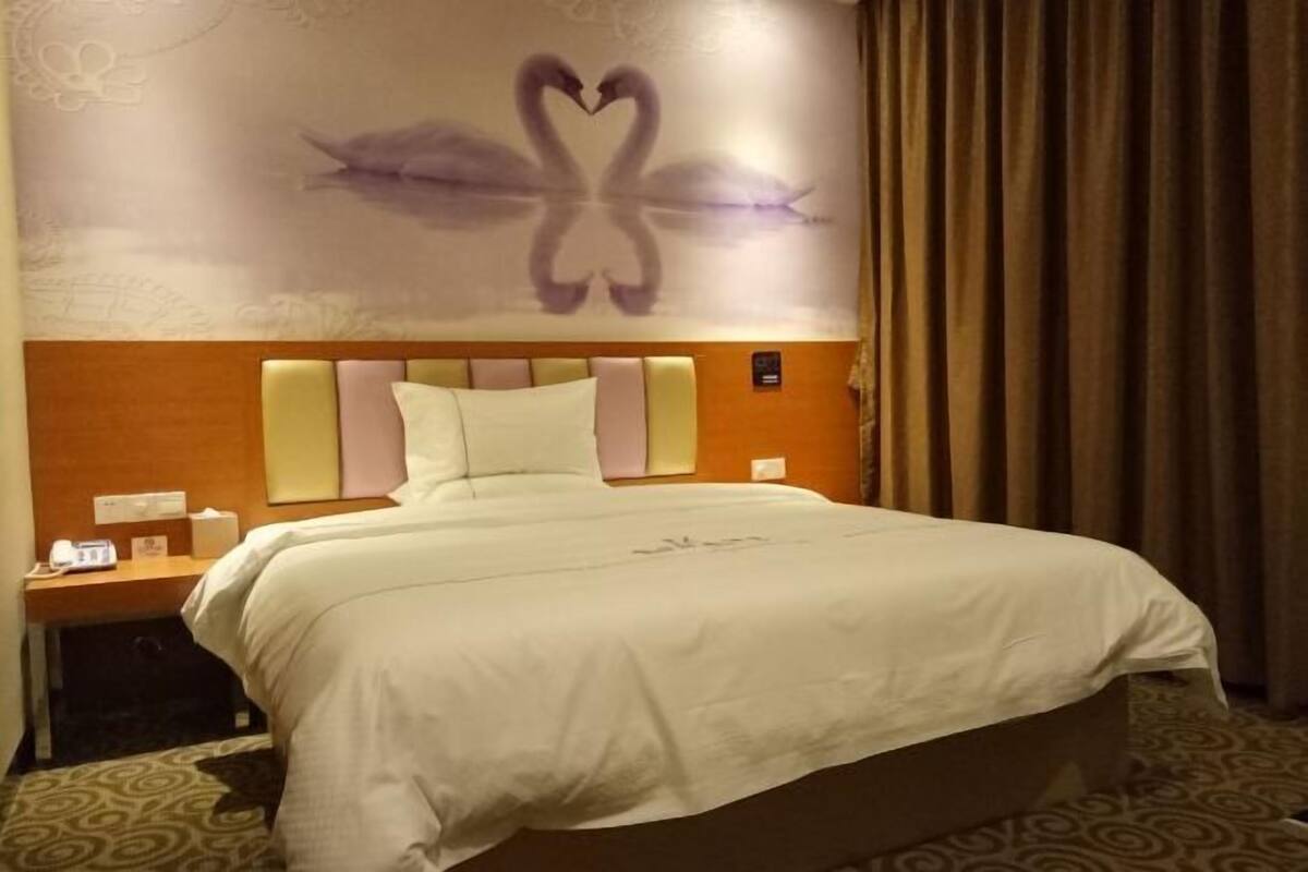 A hotel room with a bed, a nightstand, a wall with a swan design, and a curtain.