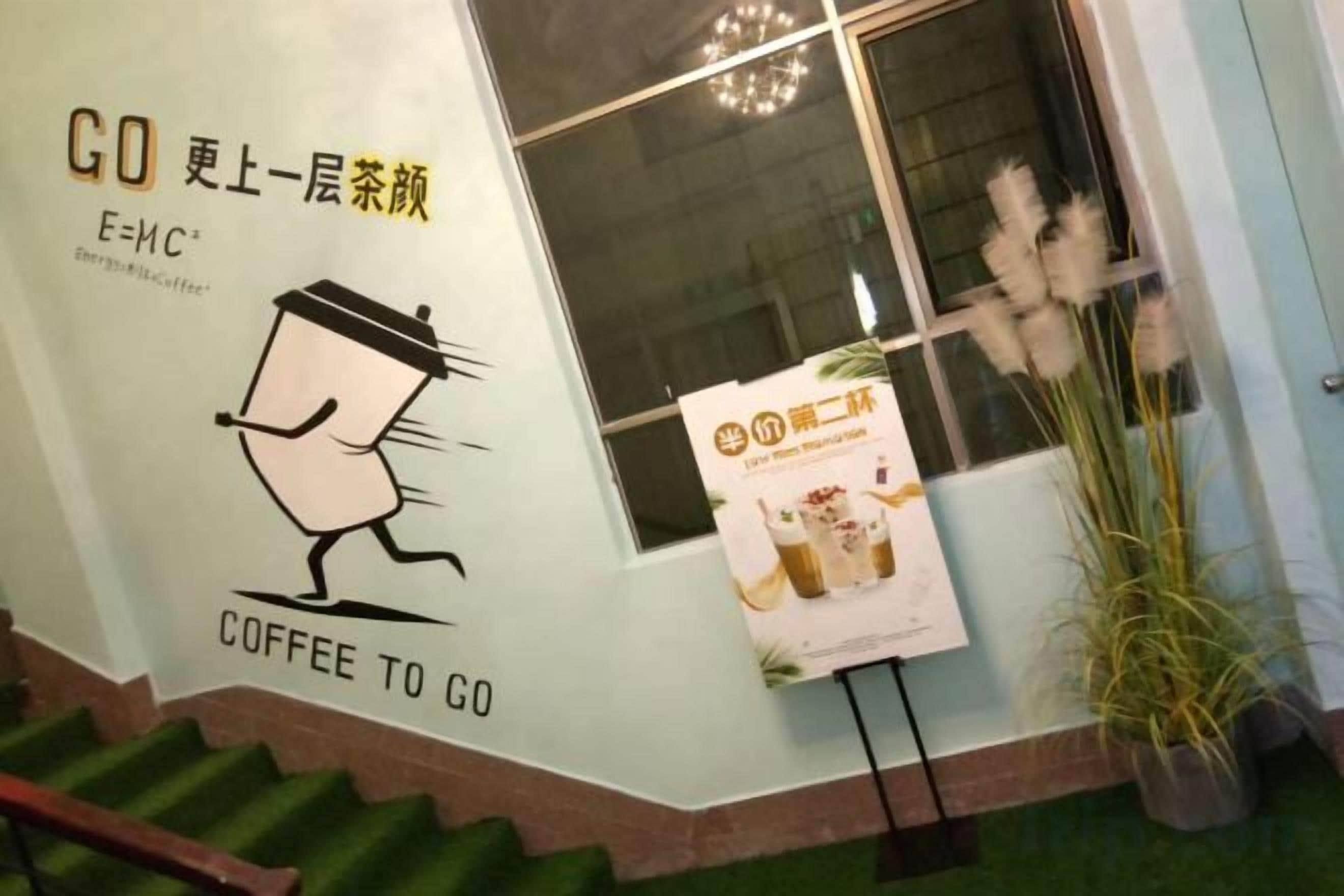 Escadaria levando a uma cafeteria, com uma placa que diz 'GO COFFEE TO GO' e um cartaz anunciando uma bebida de café.