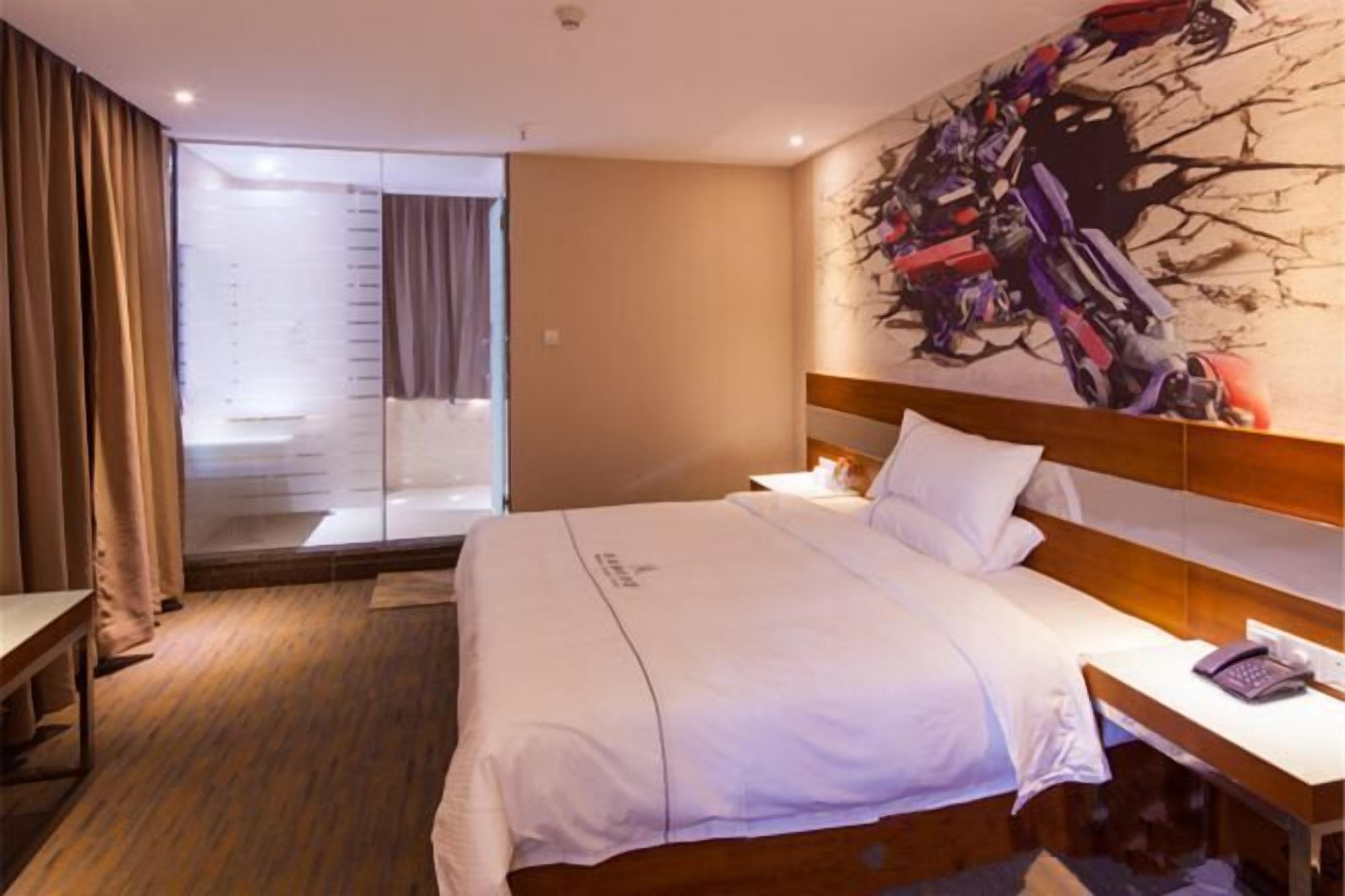 Habitación de hotel con cama, escritorio, teléfono y un cuadro abstracto grande en la pared.