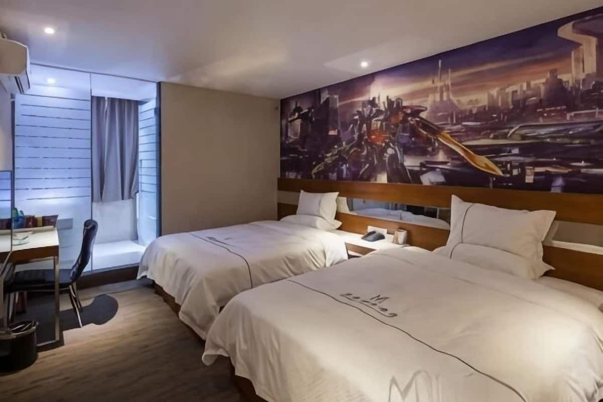 A hotel room with two beds, a desk, and a chair.