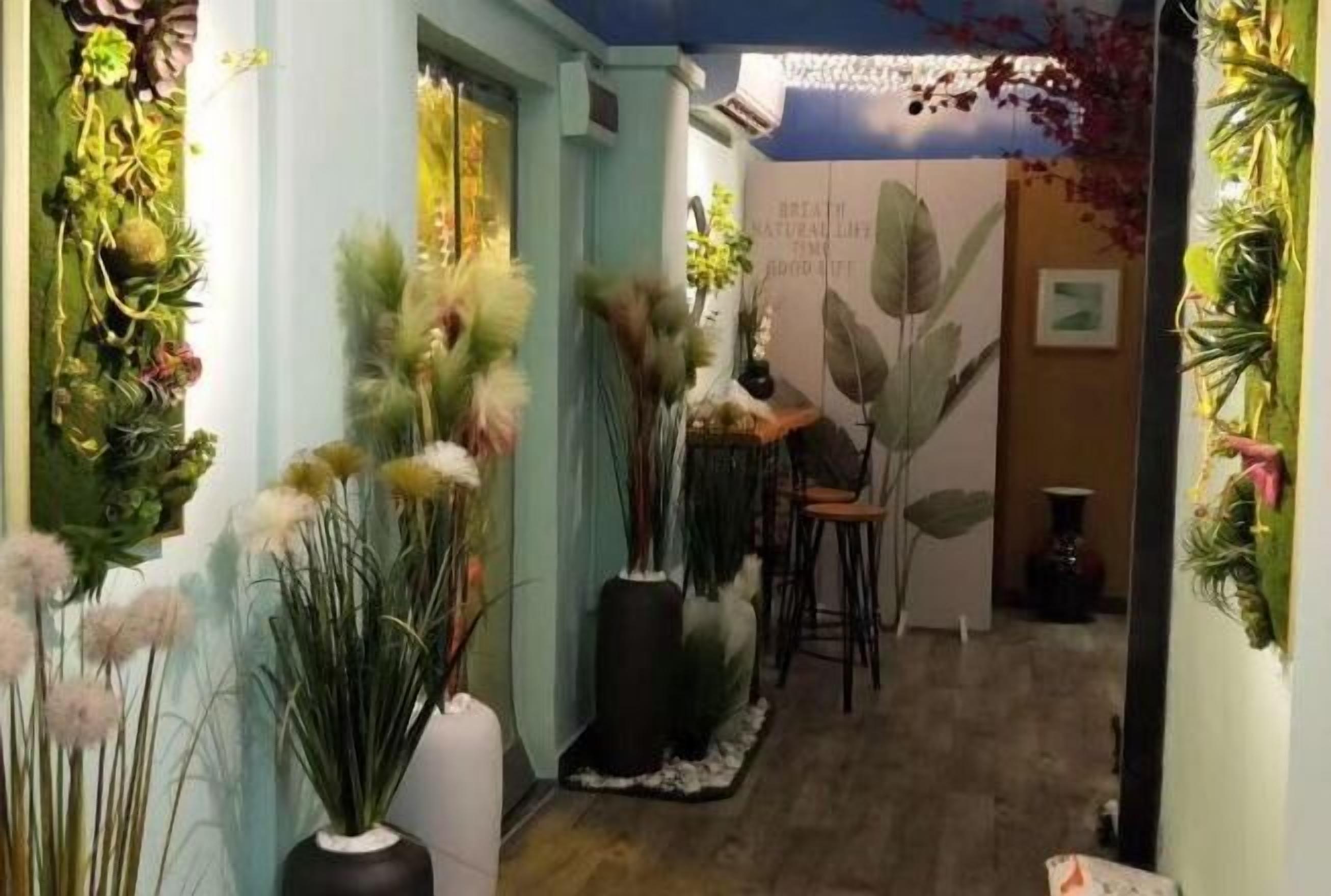 A hallway with various potted plants and a wall with a nature-themed mural.