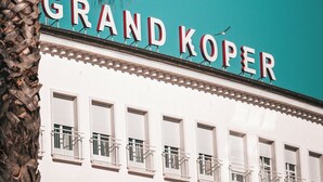 Un edificio con un letrero que dice "GRAND KOPER" y varios balcones.