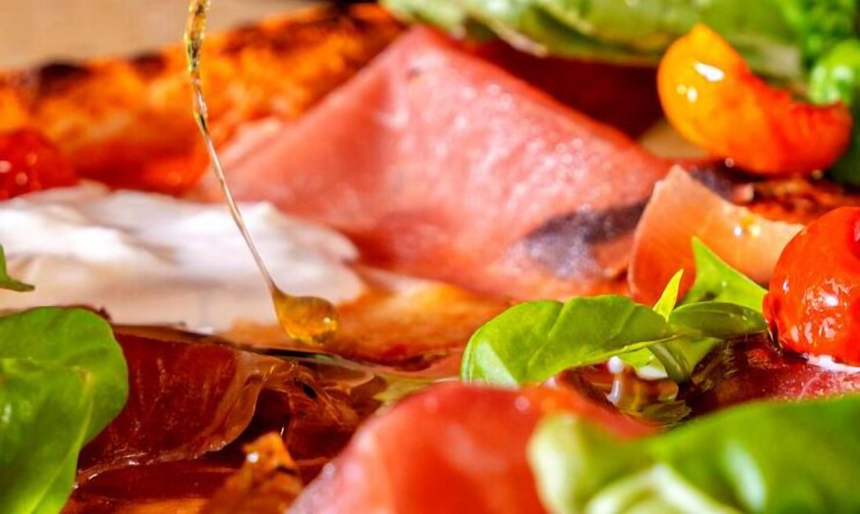 Un primo piano di un tagliere con salumi, formaggi e verdure fresche.