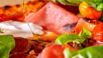 Un primo piano di un tagliere con salumi, formaggi e verdure fresche.