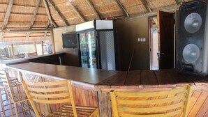 Zona de bar con sillas de madera, una barra y un refrigerador.