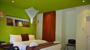 Habitación de hotel con cama, escritorio, silla, armario y obras de arte en la pared.