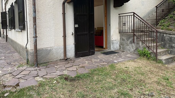 A building with a stone staircase, a black door, and a red interior visible through the doorway.